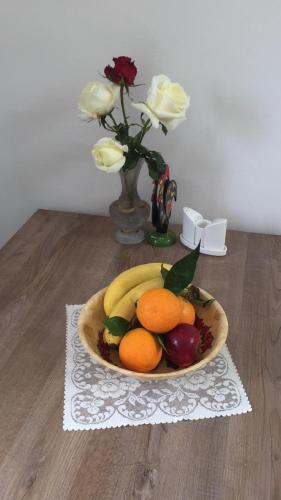 a bowl of fruit on a table with a vase with roses at Suluca Homes in Kérynia