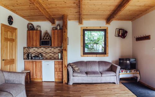 a living room with a couch and a kitchen at Rūnēnu tējas namiņš in Vidzeme