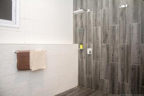 a bathroom with a shower with a wooden wall at L'imprévu in Cotonou