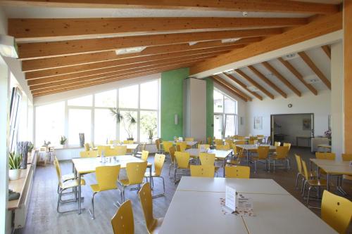 a cafeteria with tables and chairs and yellow chairs at Jugendherberge Westerland in Westerland (Sylt)