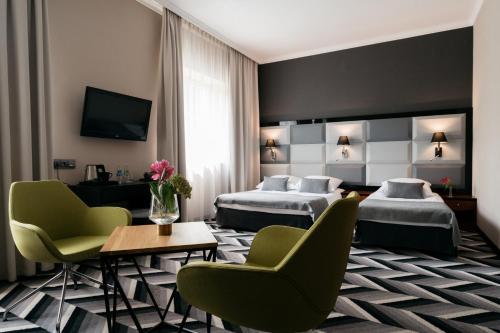 una camera d'albergo con due letti e un tavolo con sedie di Hotel Apis a Cracovia