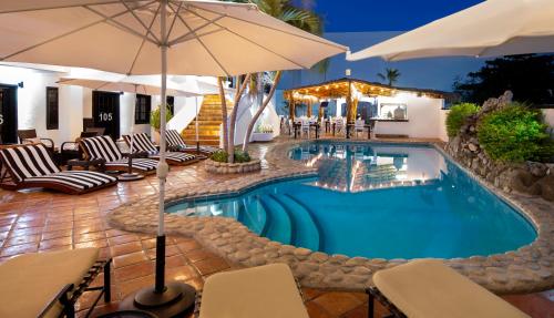 a pool with chairs and umbrellas next to a resort at La Marina Inn in San Jos&eacute; del Cabo