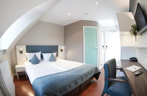a bedroom with a bed and a desk and a chair at Stadthotel Freiburg Kolping Hotels & Resorts in Freiburg im Breisgau