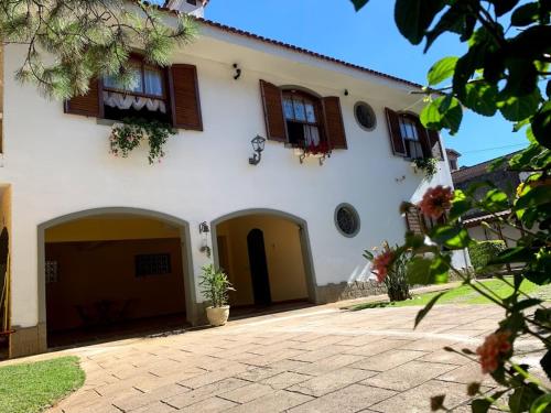 a large white house with brown windows and a driveway at Casa do Pinheiro Petrópolis in Petrópolis
