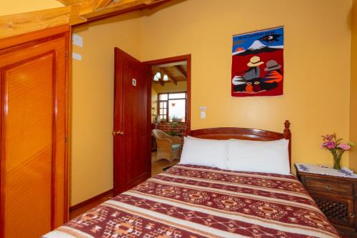 1 dormitorio con 1 cama y una pintura en la pared en Casa de Luis, en Otavalo