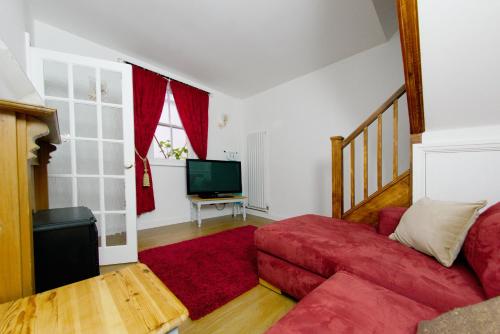 a living room with a red couch and a television at Three Queens Hotel in Burton upon Trent