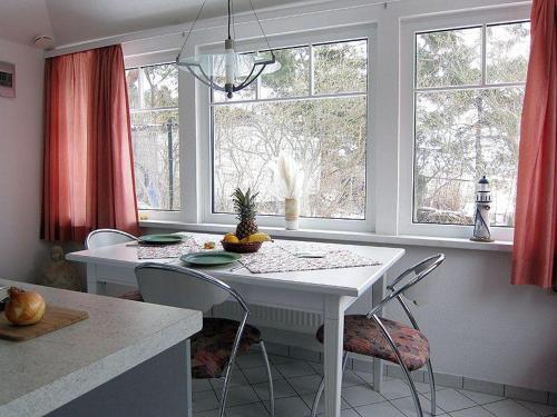 a kitchen with a white table and chairs and windows at Uns Gartenhus in Klein Zicker