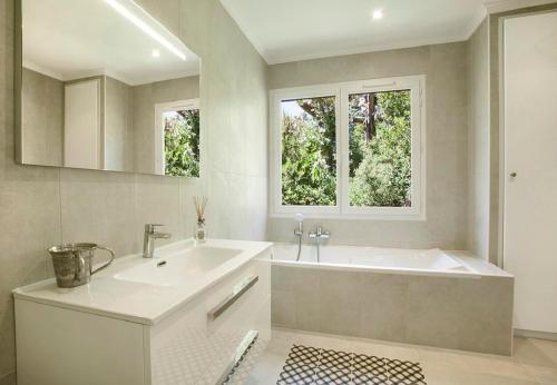 La salle de bains est pourvue d'une baignoire, d'un lavabo et de 2 fenêtres. dans l'établissement Prestigious sea view villa, à La Garonnette-Plage