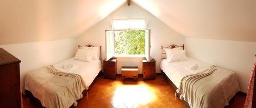 a attic room with two beds and a window at Casa Dona Beatriz in Furnas