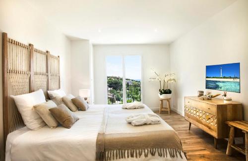 une chambre blanche avec un grand lit et une fenêtre dans l'établissement Prestigious sea view villa, à La Garonnette-Plage