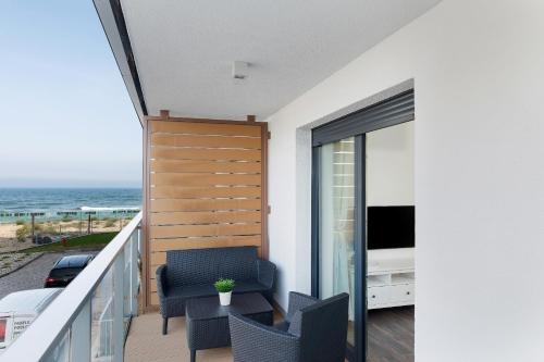 a balcony with a chair and a television and the ocean at Apartamenty Morska Fala-Gardenia in Dziwnów