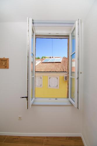 a window with a view of a yellow building at Apartments and Rooms Jospino in Mali Lošinj