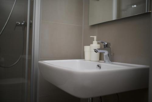 a white sink in a bathroom with a shower at Apartments and Rooms Jospino in Mali Lošinj