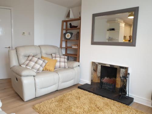 a living room with a white couch and a mirror at Coastal View in Bushmills