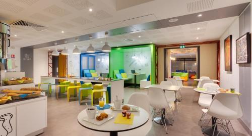 a restaurant with white tables and yellow chairs at ibis Styles Nantes Centre Gare in Nantes