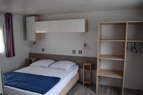 a small bedroom with a bed and shelves at Camping des Joyeux Campeurs in Pont-sur-Seine