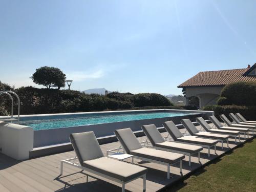 a row of lounge chairs next to a swimming pool at Villa L'Arche in Bidart