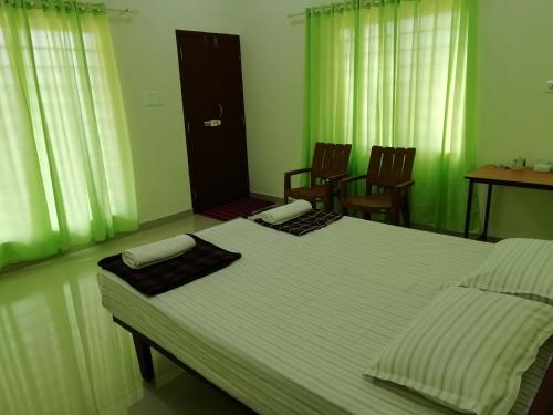 a bedroom with a large white bed with two chairs at kannur west beach homestay in Kannur