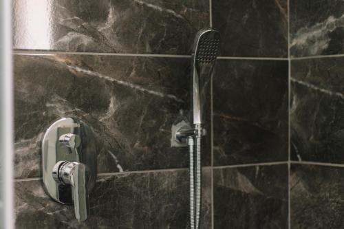 a shower in a bathroom with black tiles at Melrose House Hotel in Pamukkale