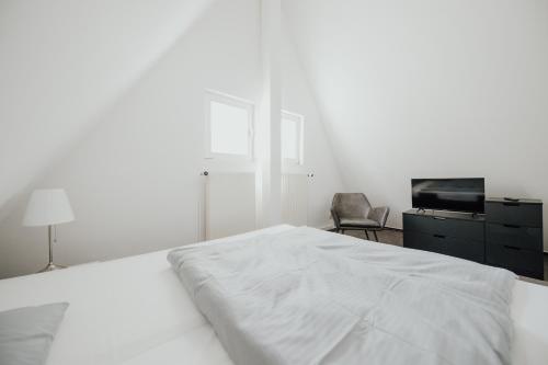 a white bedroom with a bed and a chair at Magni Boutique Hotel in Braunschweig
