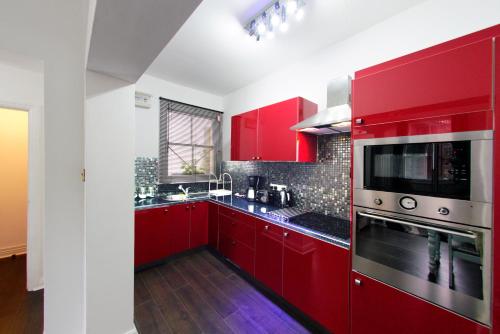 a red kitchen with red cabinets and a microwave at Three Queens Hotel in Burton upon Trent
