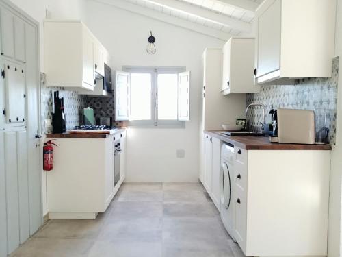 a kitchen with white cabinets and a large window at Finca Gran Cerros in Alora