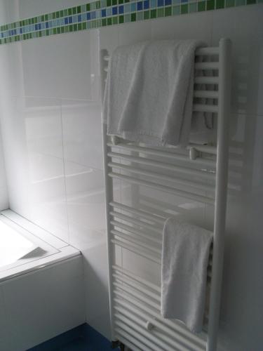 - une salle de bains blanche avec des serviettes blanches sur un porte-serviettes dans l'établissement Hôtel Le Parc, à Marly-le-Roi