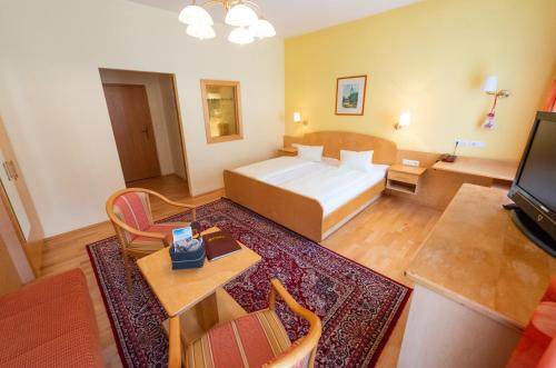 a bedroom with a bed and a living room at Landhotel Pacher in Obervellach