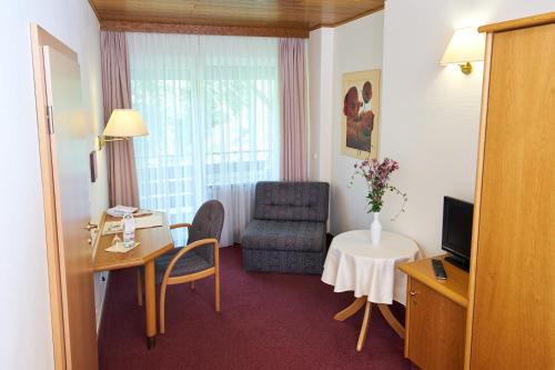 a hotel room with a desk and a chair and a table at Landhotel Krolik in Daun