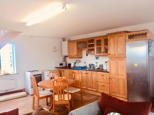 cocina con armarios de madera, mesa, mesa y sillas en Teach Beag Cois Tra, en Miltown Malbay