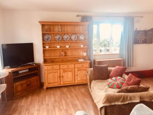 a living room with a couch and a flat screen tv at Teach Beag Cois Tra in Milltown Malbay