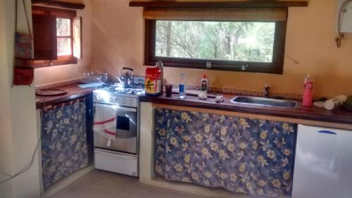 uma cozinha com um lavatório e um fogão em Casita Los Retoños en San Marcos Sierras em San Marcos Sierras