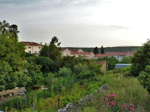 a view of a garden with houses in the background at Studio apartmani Šverko in Punat