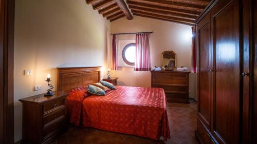 a bedroom with a bed with a red bedspread at Poggio Al Palio in San Lorenzo a Merse