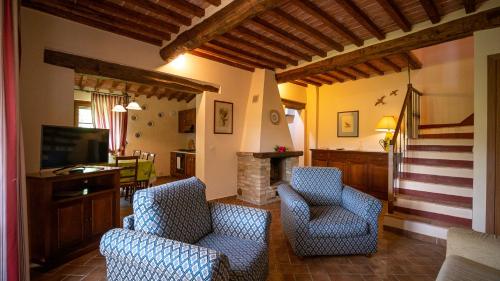 a living room with two chairs and a fireplace at Poggio Al Palio in San Lorenzo a Merse