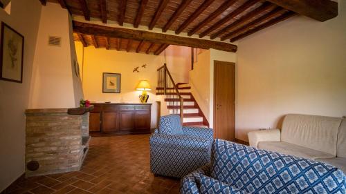 a living room with a couch and a chair and stairs at Poggio Al Palio in San Lorenzo a Merse