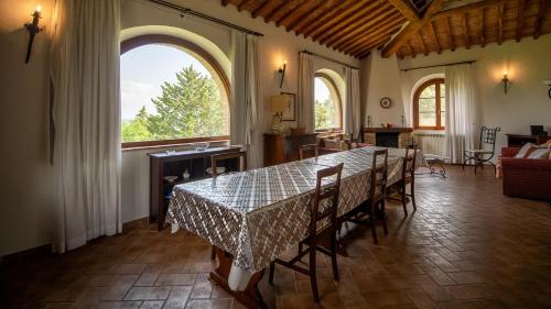 a dining room with a table and chairs and two windows at Poggio Al Palio in San Lorenzo a Merse