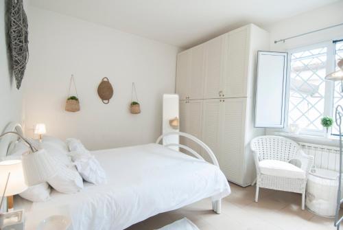 a white bedroom with a bed and a chair at Forte 27 centro in Forte dei Marmi