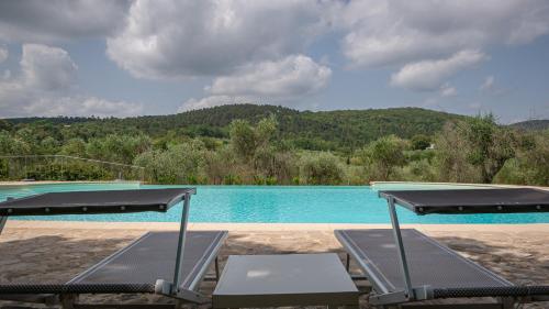 a swimming pool with two chairs in front of it at Poggio Al Palio in San Lorenzo a Merse