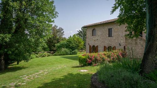 an old stone house with flowers in a yard at Poggio Al Palio in San Lorenzo a Merse