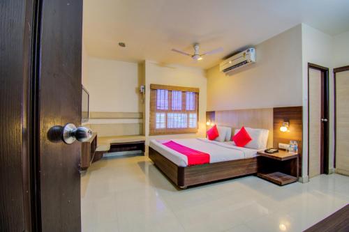 a bedroom with a bed with red pillows and a window at Sivamurugan Hotels in Kumbakonam