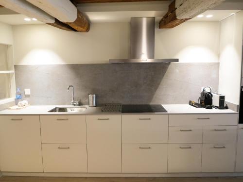 una cocina con armarios blancos y fregadero en El Oasis de la Estafeta, en Pamplona