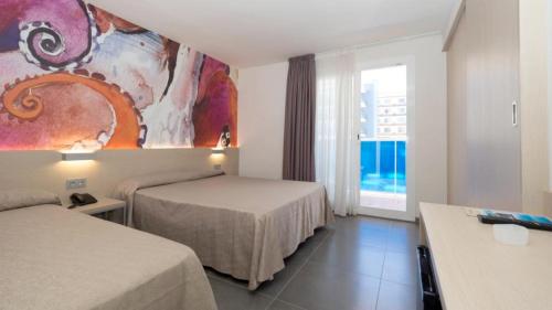 a hotel room with two beds and a window at Hotel Riviera in Santa Susanna