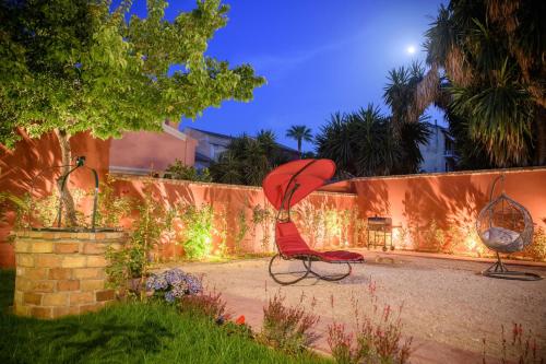 a red chair sitting in a yard next to a wall at Villa Nitsa in Corfu Town