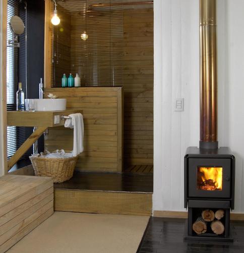a woodburning stove in a bathroom with a sink at NOI Indigo Patagonia in Puerto Natales