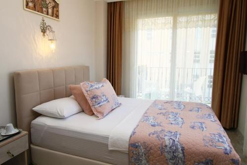 a bedroom with a bed with a window at Kandıra Butik Hotel in Çeşme