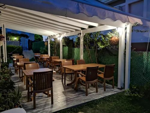 a wooden deck with tables and chairs under a white pergola at Kandıra Butik Hotel in Cesme