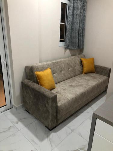 a couch with two yellow pillows in a living room at Summer Gate Hotel in Ksamil