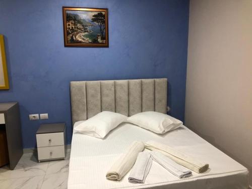 a bed with white sheets and a painting on the wall at Summer Gate Hotel in Ksamil