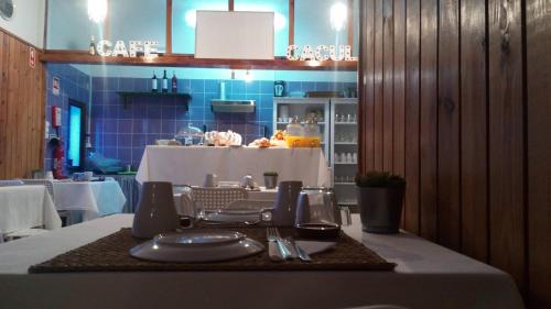a table with plates and utensils on a table in a restaurant at Caçula, Alojamento Local in Torre de Moncorvo